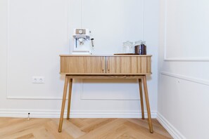 A wooden table with a coffee machine and jars on top, against a white wall with a power outlet below. - Elegant Apartment | Fireplace | 20 min Old Town (Riga)