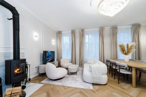 Un salon moderne doté d’une cheminée, de sièges confortables, d’un coin repas et de grandes fenêtres avec des rideaux.