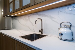 A kitchen with a marble countertop, a stainless steel sink, and a kettle. - Elegant Apartment | Fireplace | 20 min Old Town (Riga)