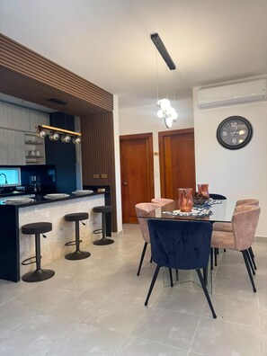 Une cuisine moderne avec un coin bar, une table à manger avec des chaises et une horloge murale.