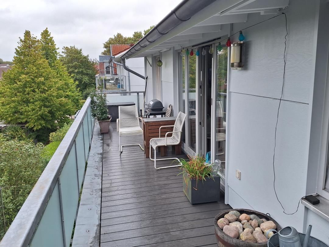 Ein überdachter Außenbereich mit Holzdeck, Grill und Sitzgelegenheit.