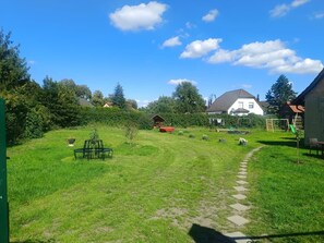 A grassy backyard with a paved path leading to a house. - Vrbo Property (Joachimsthal)