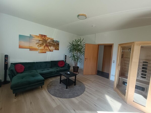 A living room with a green sofa, a coffee table, and a potted plant. - Vrbo Property (Joachimsthal)