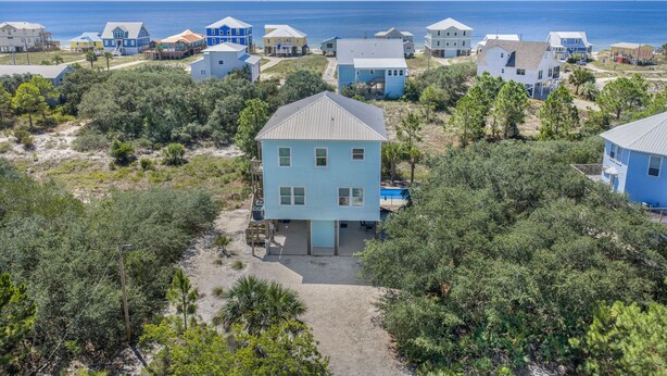 Un área residencial costera con varias casas, vista despejada al océano y una playa de arena.