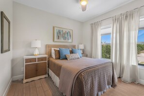 A bedroom with a bed, bedside tables, a painting, and a window with curtains. - Private Beach · Heated Saltwater Pool · Ocean View (Gulf Shores)