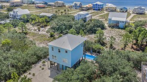 Una zona residencial costera con casas sobre pilotes, vista despejada al océano y una piscina.