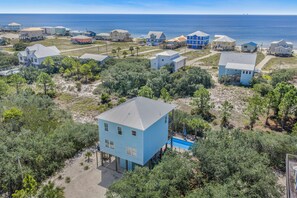 Un quartier résidentiel en bord de mer, avec des maisons sur pilotis, une vue dégagée sur l’océan et une piscine.