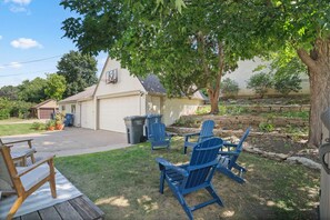 A residential backyard with a garage, a basketball hoop, outdoor seating, and a tree. - Rose Garden Retreat (Minneapolis)