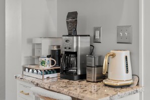 A kitchenette with a coffee maker, a kettle, a coffee bar, and a mug on the counter. - Rose Garden Retreat (Minneapolis)