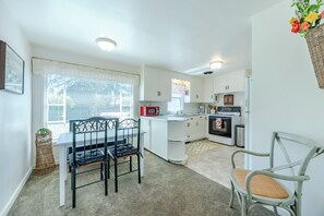 A compact kitchen with white cabinetry, a dining area with a table and chairs, and a small island with a sink.