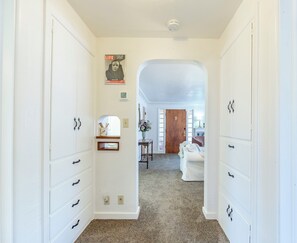 A hallway with white cabinetry, a Life magazine on the wall, and a door leading to a room with a bed and a chair.