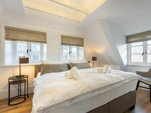A bedroom with a large bed, two bedside tables, and a window with a view. - Holiday Home Sylt 44 (Wenningstedt-Braderup)