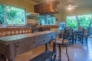 A kitchen with a wooden bench, a stove, and a dining area with chairs and a table. - Spacious 8-bedroom house in lovely Playa del Carmen with AC, walk to the beach (Playa del Carmen)