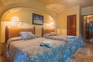 A hotel room with two beds, each with a floral bedspread, a framed picture on the wall, and a wooden door. - Spacious 8-bedroom house in lovely Playa del Carmen with AC, walk to the beach (Playa del Carmen)