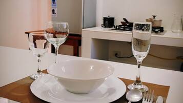 Een keuken met een eettafel voor twee personen, compleet met een kom, borden, wijnglazen en bestek.