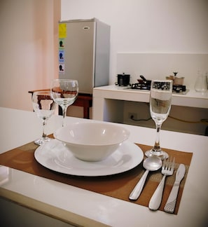 A kitchen with a dining table set for two, including a bowl, plates, wine glasses, and cutlery. - Cozy 1-bedroom apartment in fantastic Puerto Baquerizo Moreno with AC (Puerto Baquerizo Moreno)