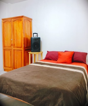 A bedroom with a bed, a wooden wardrobe, and a small table with a suitcase. - Cozy 1-bedroom apartment in fantastic Puerto Baquerizo Moreno with AC (Puerto Baquerizo Moreno)