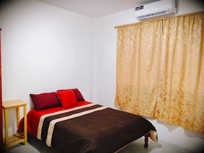 A single bed with a brown and white bedspread, two red pillows, and a wooden nightstand to the left. - Cozy 1-bedroom apartment in fantastic Puerto Baquerizo Moreno with AC (Puerto Baquerizo Moreno)