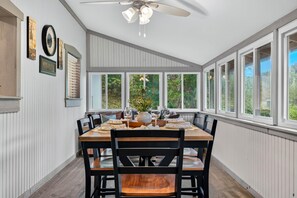 A dining area with a large table, chairs, and a ceiling fan.