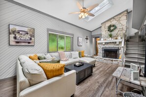 A modern living room with a sectional sofa, a fireplace, and a ceiling fan. - Couples Delight, Pet Friendly, close to Brown County State Park! (Nashville)