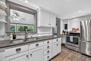 A modern kitchen with white cabinetry, stainless steel appliances, and a central island.