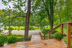 A wooden deck leading to a park area with trees and a gravel path. - Couples Delight, Pet Friendly, close to Brown County State Park! (Nashville)