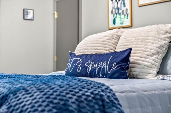 A bed with a blue blanket and two pillows, one with text and the other plain. - Couples Delight, Pet Friendly, close to Brown County State Park! (Nashville)