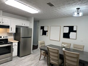 A modern kitchen with stainless steel appliances, a dining table with chairs, and abstract art on the walls. - Rome Sweet Rome! Spacious 4-Bedroom Home with AC (Rome)