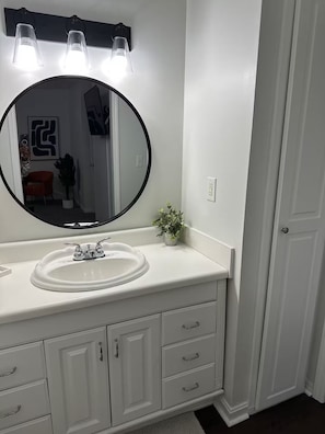 A bathroom with a white vanity, a round mirror, and a light fixture above the mirror. - Rome Sweet Rome! Spacious 4-Bedroom Home with AC (Rome)