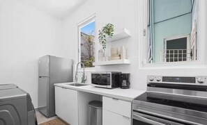 Eine kleine Küche mit Kühlschrank, Mikrowelle, Kaffeemaschine und Backofen.