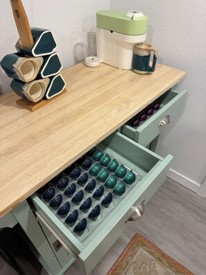 Uma mesa de madeira com uma gaveta verde contendo várias chávenas azul-escuras.