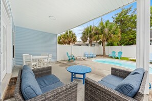 An outdoor patio with wicker furniture, a pool, and palm trees. - 5BR | Sleeps 15 | Pool | Close To The Beach | 709 (North Myrtle Beach)