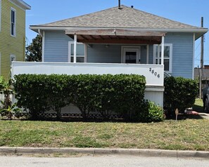 A single-story house with a front porch, a mailbox, and a clear sky. - Pleasure Pier View 2BR · Steps to Seawall (Galveston)