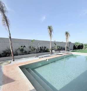 A swimming pool with a clear blue water surface, surrounded by a concrete wall and various plants. - 3-bedroom, 3-bathroom house with a private pool—not overlooked—featuring a hammam and views of the Atlas Mountains (Marrakech-Safi)