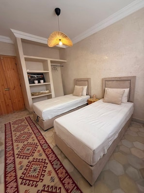 A bedroom with two beds, a wardrobe, a shelf unit, and a patterned rug. - 3-bedroom, 3-bathroom house with a private pool—not overlooked—featuring a hammam and views of the Atlas Mountains (Marrakech-Safi)