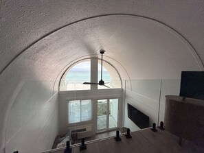 A high-ceilinged room with a curved ceiling, large windows, and a view of the beach. - Newly Remodeled & Pet Friendly - Sunset Surfside (Panama City Beach)