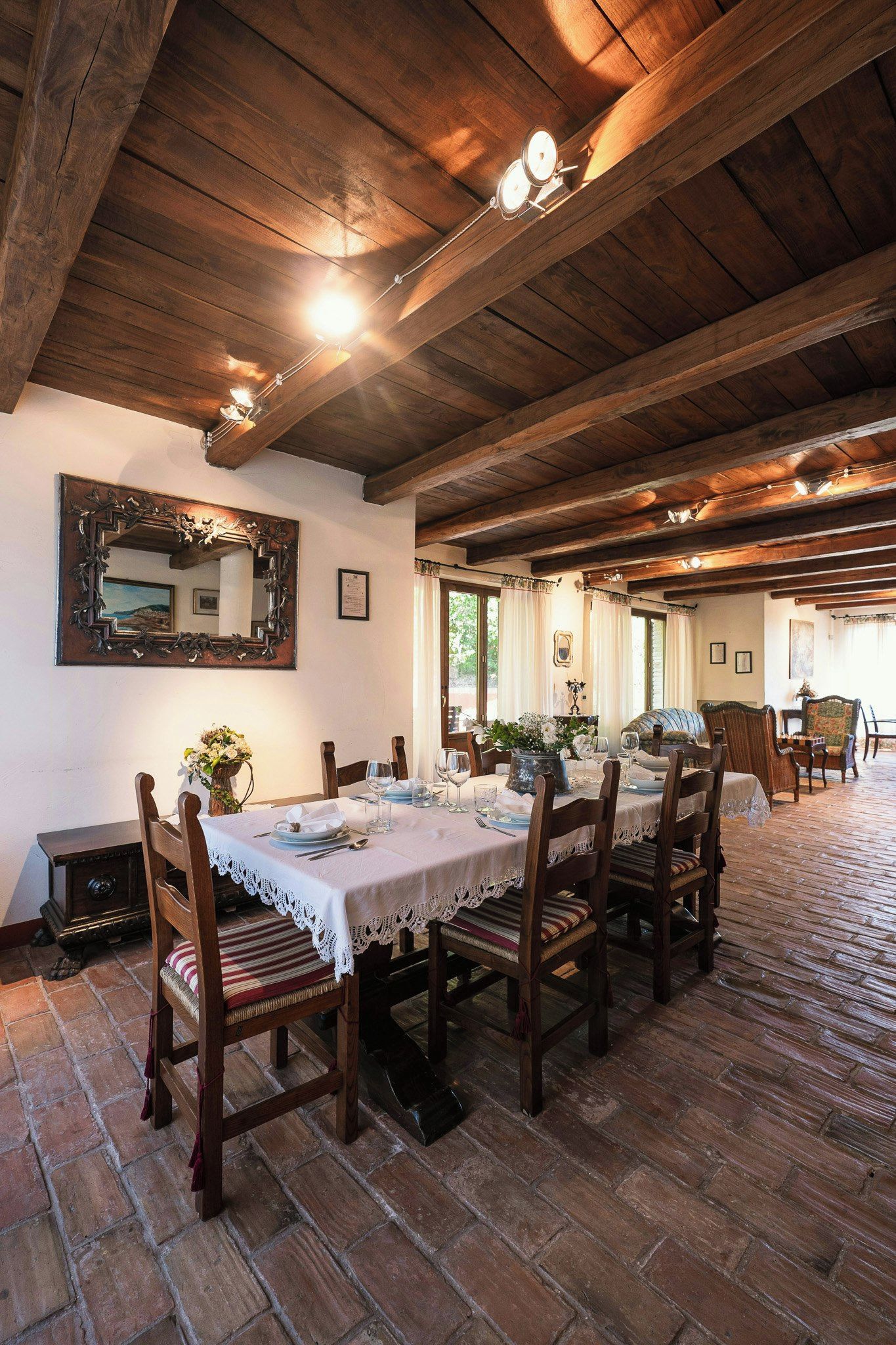 Un espace repas avec un sol en briques, des poutres en bois au plafond et une table dressée pour quatre personnes.