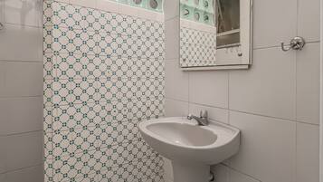 Een badkamer met een betegelde muur met een patroon, een wastafel en een spiegel.