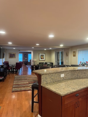 A spacious kitchen with a granite countertop, wooden cabinets, and a dining area with chairs and a table. - OVERSIZED 1BR/1BA Winter Seasonal Rental (New Hampton)