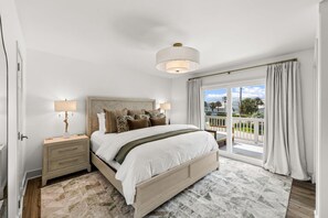 A bedroom with a bed, nightstands, a lamp, and a view of the outdoors. - Editorial Townhome on Quiet Beach • 3mi to 30A (Panama City Beach)