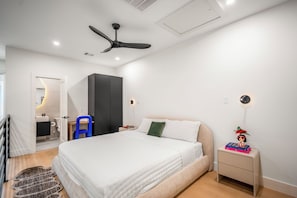 Une chambre moderne comprenant un lit, un bureau, une chaise, une armoire et un ventilateur de plafond.