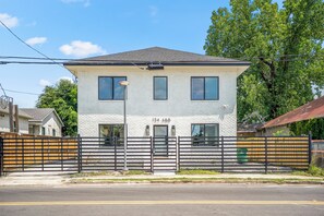 A two-story building with a white brick facade, numbered 134 A&B, and a black metal fence in front.