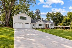 Une maison à deux étages avec une allée menant à l’entrée, un garage et une pelouse bien entretenue.