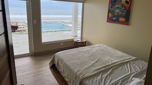 A bedroom with a large window overlooking a pool and the ocean. - 7-bedroom Beach Front house in Play Miramar with AC (Miramar)