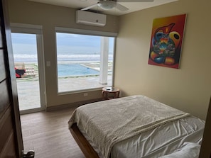 Un dormitorio con un ventanal grande que da a una piscina y al océano.