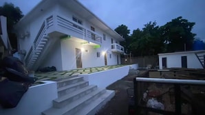 A modern two-story house with a staircase leading to the entrance, a fenced yard, and a small adjacent building. - 7-bedroom Beach Front house in Play Miramar with AC (Miramar)