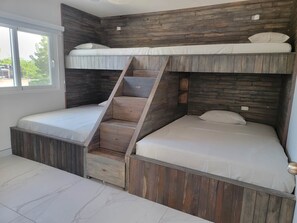 A bunk bed room with a wooden headboard, a window, and a built-in desk.