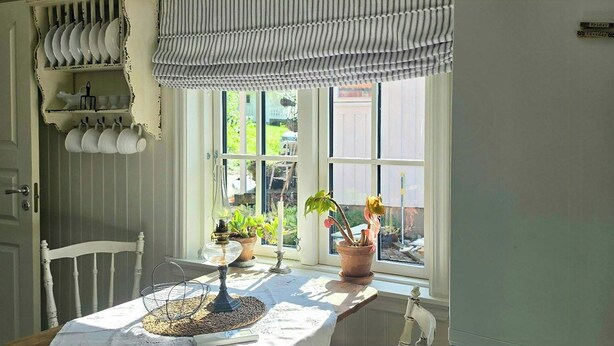 Ein Essbereich mit einem Tisch für zwei Personen, einem Fenster mit Blick auf Grünflächen und einem weißen Kühlschrank.