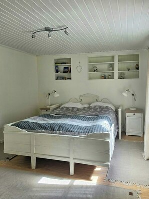 A bedroom with a bed, bedside tables, a ceiling fan, and built-in shelves with books and decorative items. - Renovated guesthouse with courtyard in Ljungskile (Västra Götalands län)