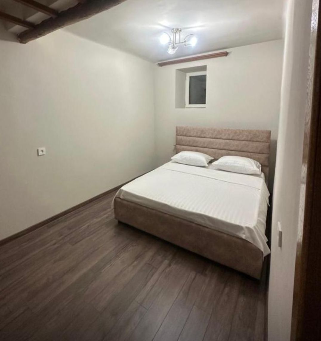 A bedroom with a bed, a small window, and a ceiling fan.